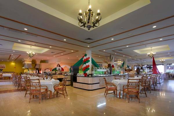Innenansicht des Restaurants im Grand Palladium Kantenah Resort & Spa mit Tischen, Stühlen und Dekor.