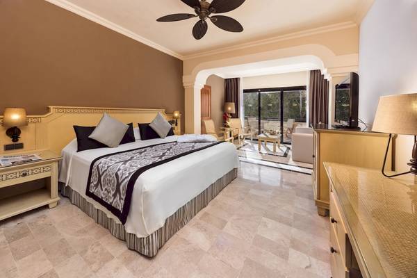 Suite-Schlafzimmer im Grand Palladium Kantenah Resort mit Kingsize-Bett, Dekor und Terrassenzugang.