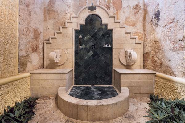 Steindusche im Grand Palladium Kantenah Resort & Spa mit schwarzen Mosaiken und Marmorbank.