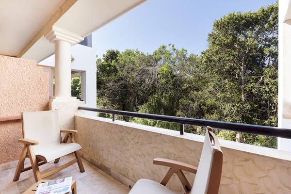 Terrasse des Grand Palladium Kantenah Resorts & Spa mit zwei Stühlen und einem Tisch.