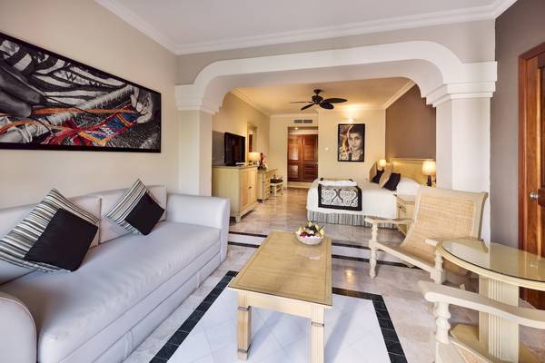 Innenansicht der Suite im Grand Palladium Kantenah Resort mit Wohnzimmer und Schlafzimmerbereich.