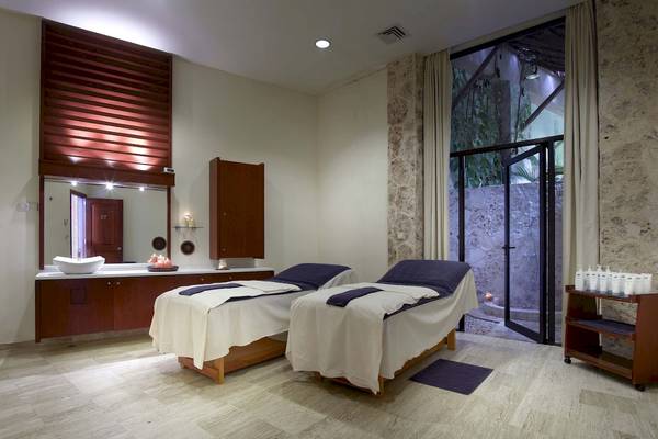 Zwei Massageliegen im Wellnessbereich des Grand Palladium Kantenah Resort & Spa mit Holzmöbeln und Fliesenboden.