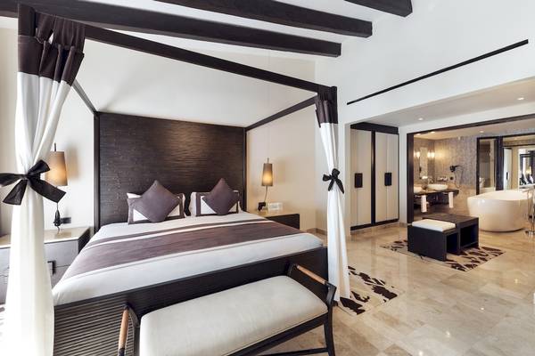 Schlafzimmer im Grand Palladium Kantenah Resort & Spa mit Himmelbett, zwei Nachttischen und einem Badezimmer.
