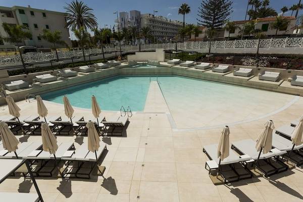 Pool-Lounge-Bereich im Caserio Hotel mit vielen Liegestühlen und Sonnenschirmen.