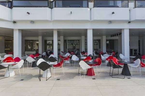 Terrasse des Caserio Hotels mit rot-weißen Sesseln und Tischen, modernes Design.