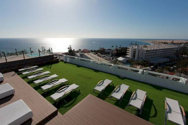 Dachterrasse des Caserio Hotels mit weißen Liegen und Blick auf das Meer