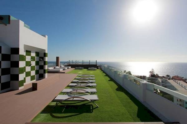 Dachterrasse des Caserio Hotels mit Sonnenliegen und Blick auf das Meer