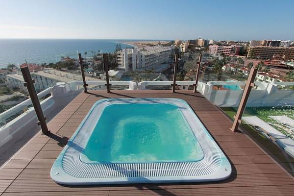 Dachansicht eines blauen Whirlpools im Caserio Hotel mit Blick auf die Stadt und das Meer.