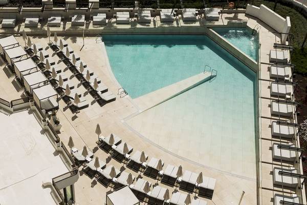 Obenliegende Ansicht des Poolbereichs des Caserio Hotels mit vielen Liegestühlen und Sonnenschirmen