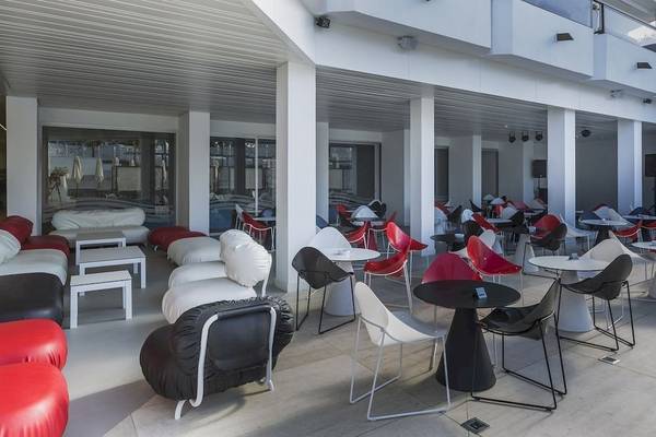 Loungebereich des Caserio Hotels mit weißen und roten Stühlen und Tischen.