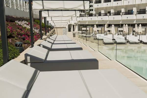 Lounge-Bereich des Caserio Hotels mit weißen Sonnenliegen und Swimmingpool.