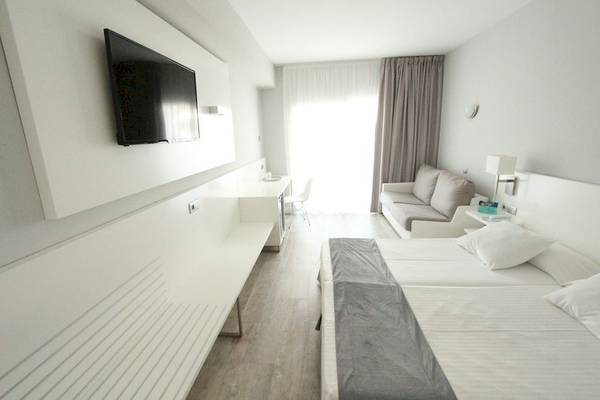 Innenansicht eines Zimmers im Caserio Hotel mit Doppelbett, Sofa, Fernseher und Schreibtisch