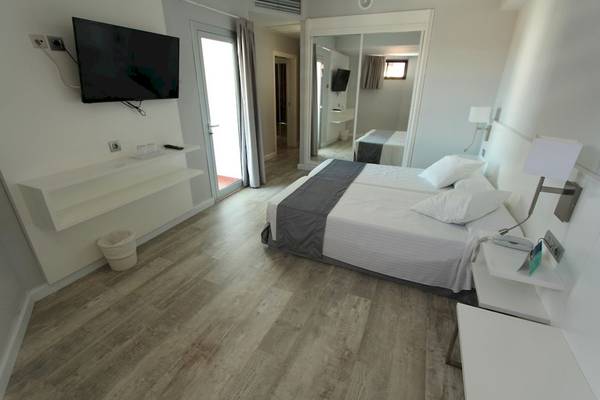 Doppelzimmer im Caserio Hotel mit zwei Betten, Fernseher und einem Badezimmerspiegel.