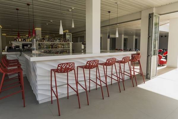 Bar-Lounge im Caserio Hotel mit roten Stühlen und einer Theke mit vielen Flaschen.