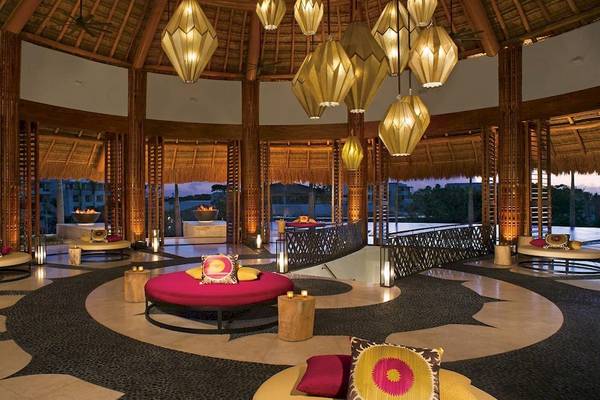 Innenraum des Hotel-Lobby-Bereichs von Secrets Akumal Riviera Maya mit Loungemöbeln, Beleuchtung und Aussicht.