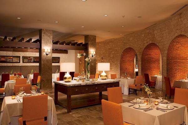 Innenbereich des Restaurants im Secrets Akumal Riviera Maya mit runden Bögen und Steinwänden.