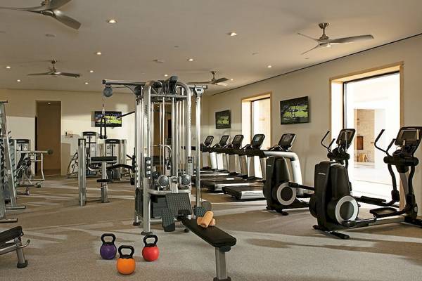 Fitnessstudio im Hotel Secrets Akumal Riviera Maya mit verschiedenen Trainingsgeräten und Fernsehern.
