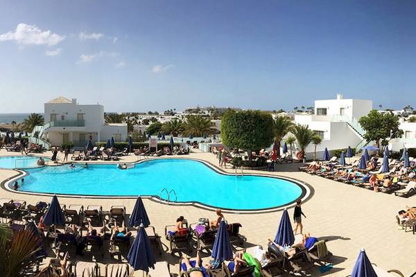 Poolbereich des Lanzarote Village Hotels mit vielen Gästen und Sonnenschirmen.