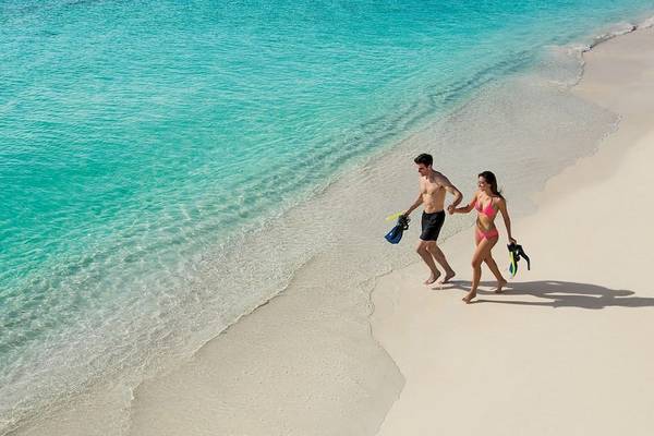 Ein Paar mit Schnorchelausrüstung läuft am Strand des Secrets Akumal Riviera Maya.