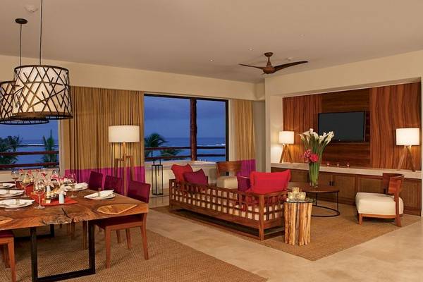 Wohnzimmer im Secrets Akumal Riviera Maya mit Blick auf das Meer, Tisch und Sofa.