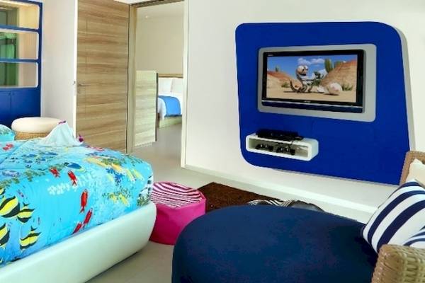 Doppelzimmer in der Ferienwohnung des Holiday Inn Mai Khao Resort mit zwei Betten, blauen Wänden und Fernseher.