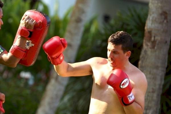 Zwei Männer boxen im Holiday Inn Mai Khao Resort, einer mit roten Handschuhen, der andere hält einen roten Schild.