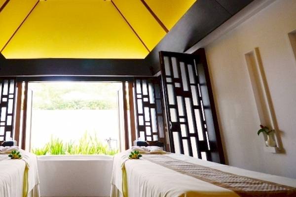 Massageraum im Holiday Inn Mai Khao Resort mit zwei Massageliegen, einem gelben Dach und offenen Türen.