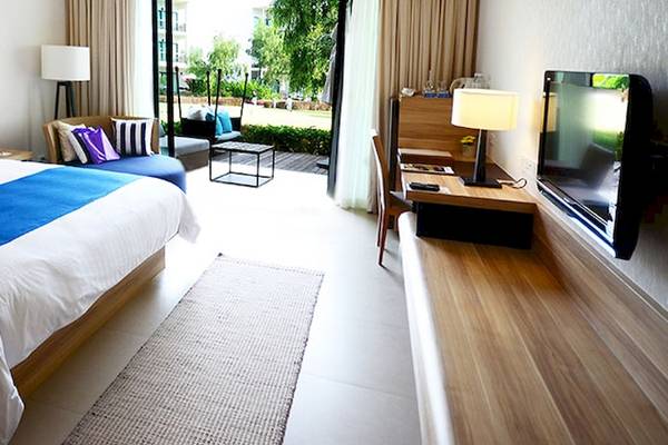 Zimmer im Holiday Inn Mai Khao Resort mit Doppelbett, Nachttischen, Fernseher und Balkon