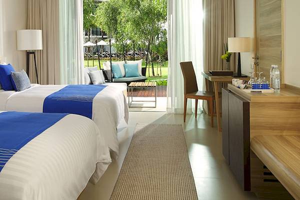 Doppelzimmer im Holiday Inn Mai Khao Resort mit zwei Betten, blauen Kissen und offenem Balkon.