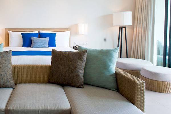 Innenansicht des Holiday Inn Mai Khao Resort Zimmers mit einem großen Bett und bequemen Sofas.