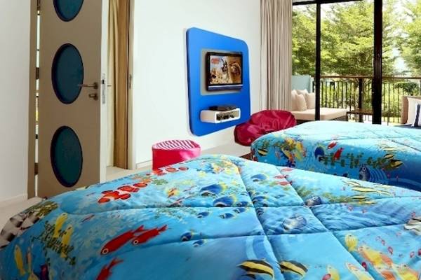 Zweibettzimmer mit Unterwasserthema im Holiday Inn Mai Khao Resort, mit bunten Bettdecken und Fernseher an der Wand.