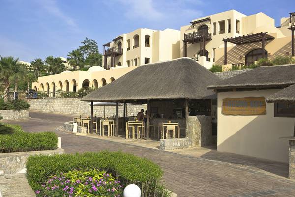 Außenansicht des Cove Rotana Resorts mit Bar und Hotelgebäude im Hintergrund.