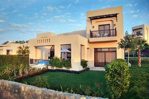 Außenansicht der Villa im Cove Rotana Resort mit Swimmingpool und gepflegtem Garten