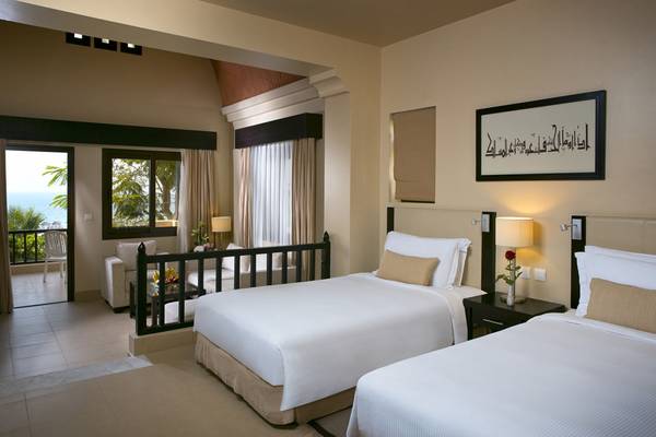 Doppelzimmer mit Meerblick im Cove Rotana Resort, zwei Betten, Balkon, Wohnzimmer mit Möbeln und Gemälde.