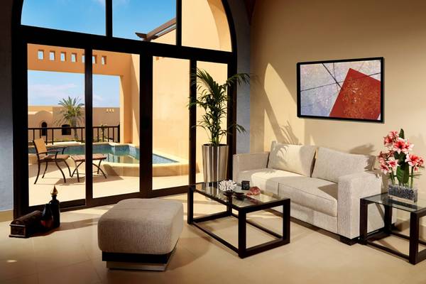 Wohnzimmer mit Sofa, Tisch, Couchtisch, Pflanzen und Blick auf einen Swimmingpool.