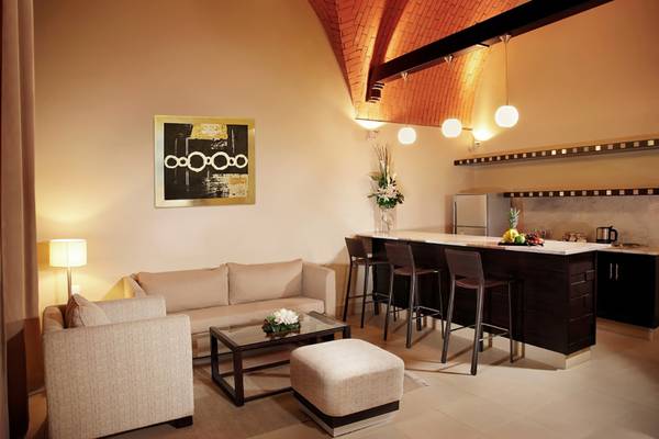 Wohnbereich im Cove Rotana Resort mit Couch, Tisch und Bar.