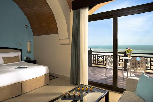 Hotelzimmer mit Meerblick im Cove Rotana Resort mit Bett, Balkon und Ausblick auf den Ozean.