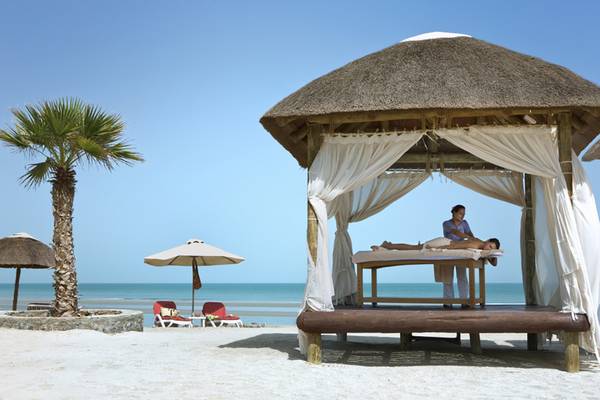 Massage unter einer Strohhut am Strand des Cove Rotana Resorts