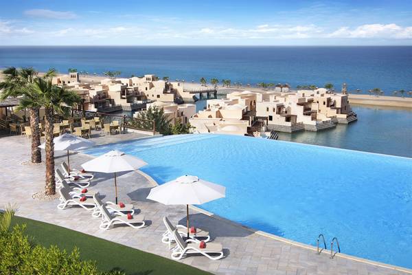 Außenpool des Cove Rotana Resorts mit Blick auf das Meer und die Hotelanlage.