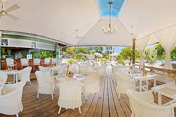 Terrasse des Couples Negril Hotels mit weißen Möbeln und Decken unter freiem Himmel.