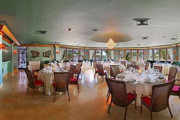 Innenansicht des Restaurants im Couples Negril Hotel mit mehreren gedeckten Tischen und Stühlen.