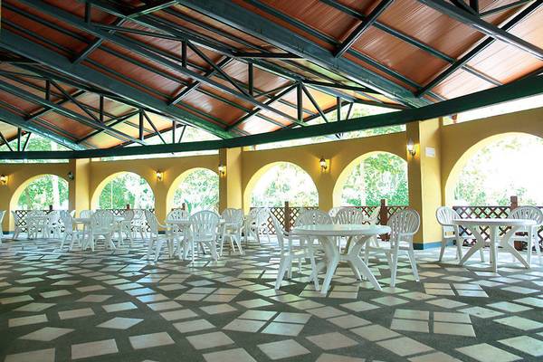 Innenansicht der Terrasse im Punta Leona Hotel mit weißen Tischen und Stühlen und braunem Dach.