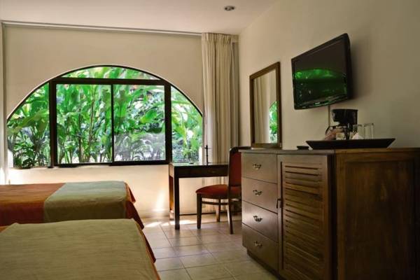 Doppelzimmer im Punta Leona Hotel mit zwei Betten, Fernseher und Schreibtisch.