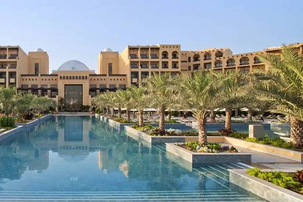 Außenbereich des Hilton Ras Al Khaimah Beach Resort mit Swimmingpool und tropischen Bäumen.