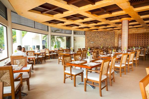 Innenansicht des Restaurants im Reef Coco Beach Hotel mit gedeckten Tischen und Stühlen.