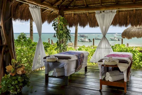 Zwei Massagestühle im Freien mit Blick auf das Meer und weiße Vorhänge am Hotel The Reef Coco Beach.