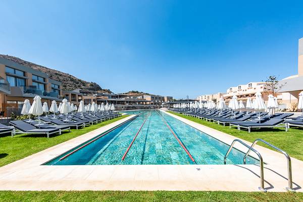 Außenpool des Kiani Beach Resorts mit vielen Sonnenliegen und Sonnenschirmen.