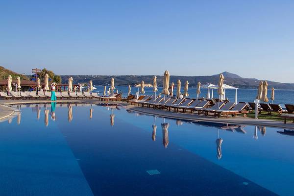 Außenpool des Kiani Beach Resort mit vielen Liegestühlen und Sonnenschirmen am Strand