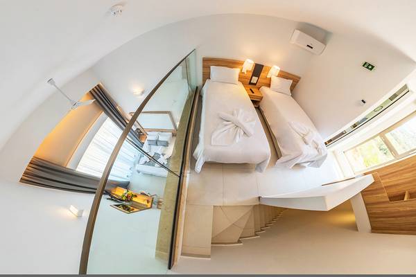 Luftbild einer Suite im Kiani Beach Resort mit zwei Betten, Spiegel und moderner Einrichtung.