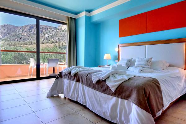 Zimmer mit Bett und Terrassenblick im Kiani Beach Resort mit blauen Wänden und Panoramafenstern
